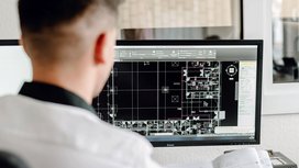 In einem hellen Büro analysiert ein Architekt einen digitalen Plan, der verschiedene Räume und Layouts darstellt.
