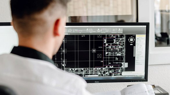 In einem hellen Büro analysiert ein Architekt einen digitalen Plan, der verschiedene Räume und Layouts darstellt.