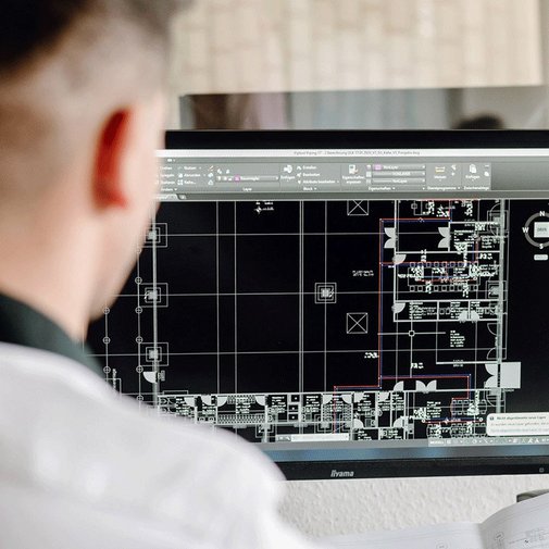 In einem hellen Büro analysiert ein Architekt einen digitalen Plan, der verschiedene Räume und Layouts darstellt.