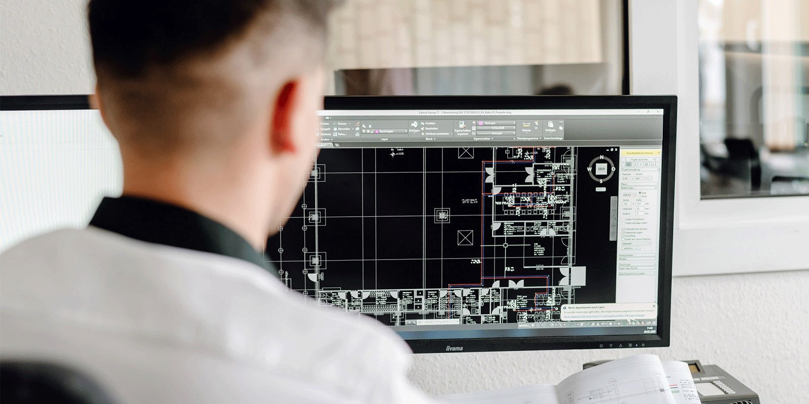 In einem hellen Büro analysiert ein Architekt einen digitalen Plan, der verschiedene Räume und Layouts darstellt.