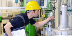 Ein Mann mit Bauhelm kontrolliert eine Gasleitung