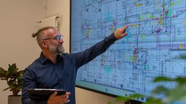 Mitarbeiter von Büürma zeigt auf einen technischen Gebäudeplan auf einem großen Bildschirm