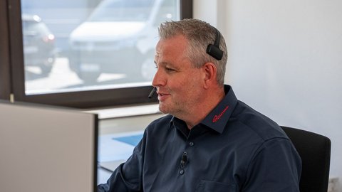 Mitarbeiter von Büürma sitzt im Büro mit Headset vor einem Computerarbeitsplatz