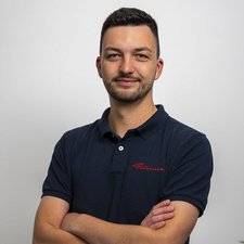 Porträt eines selbstbewussten Mannes in dunklem Poloshirt Der Mann trägt ein dunkelblaues Polohemd mit rotem Schriftzug und hat einen selbstbewussten Ausdruck im Gesicht.