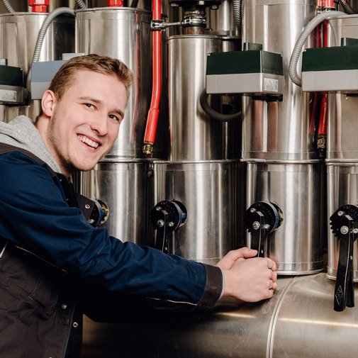 Der Techniker in blauer Arbeitskleidung betätigt Hebel an einer großen Maschine, um sie zu steuern.