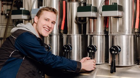 Der Techniker in blauer Arbeitskleidung betätigt Hebel an einer großen Maschine, um sie zu steuern.