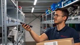 Mitarbeiter von Büürma scannt im Lager einen Artikel aus einem Regal und hält eine Kiste
